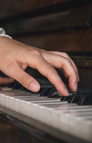 Female hands playing the old piano, close-up. Female hands play on an old wooden piano, close-up.